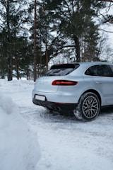 A sleek luxury SUV parked on a snowy alpine mountain road at sunrise.