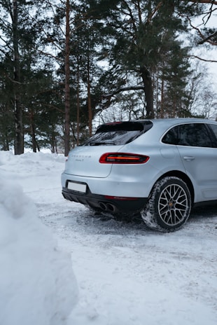 A sleek luxury SUV parked on a snowy alpine road with majestic mountains in the background.