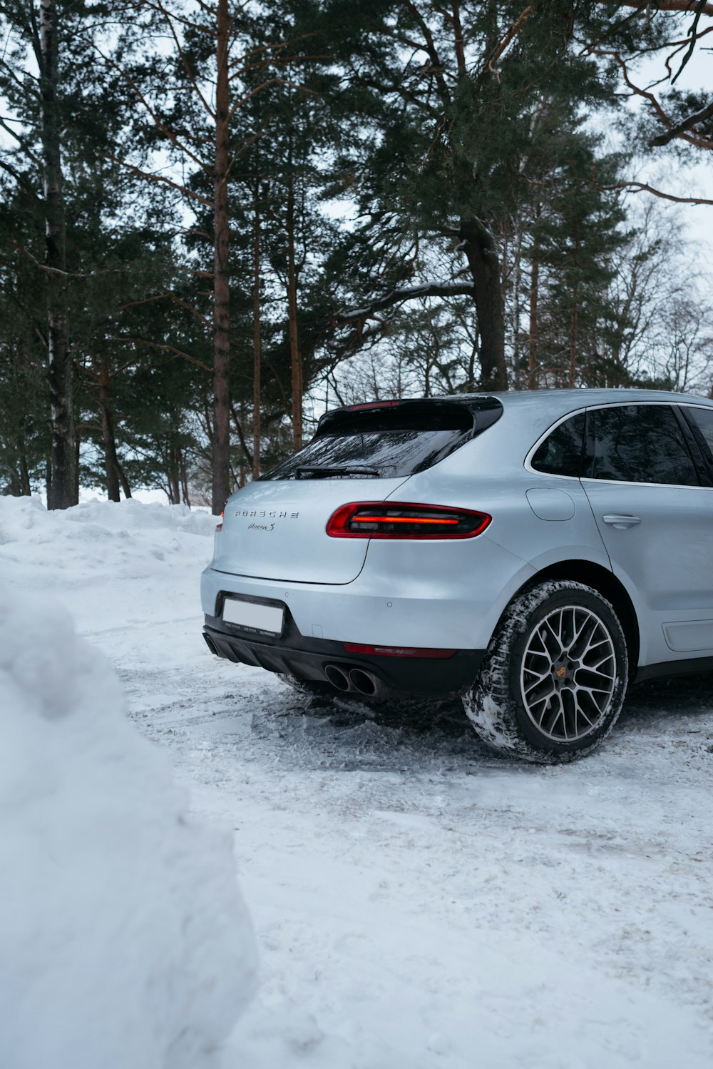 a silver porsche cayen is parked in the snow