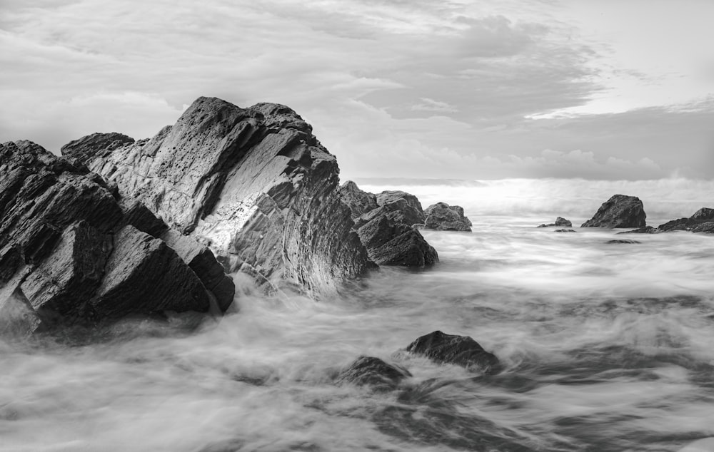 a black and white photo of rocks in the ocean