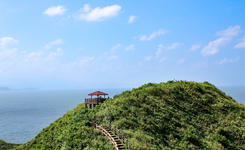 a gazebo sitting on top of a lush green hillside next to the ocean