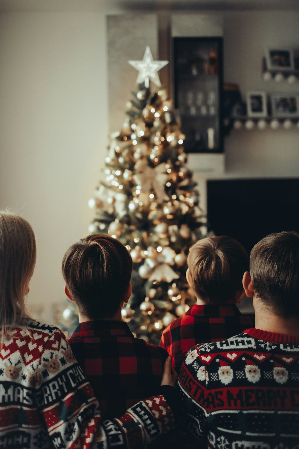 three children sitting in front of a christmas tree