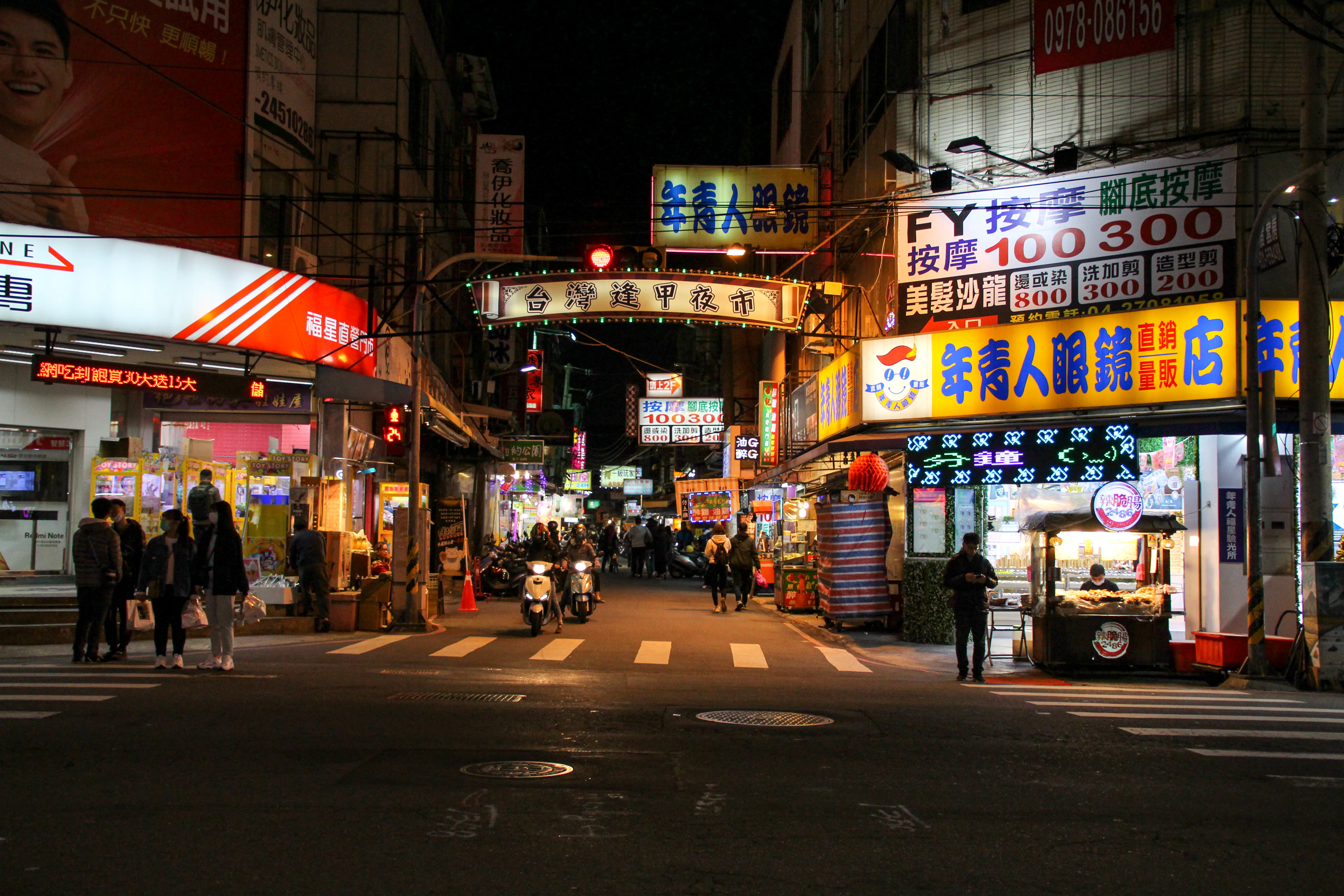 City street at night with people walking on the sidewalk