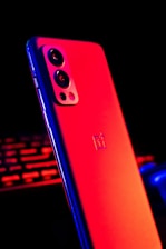 A sleek smartphone showing the modo juego app interface with dark mode, red highlights, and glowing buttons.