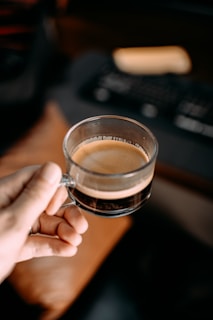 Close-up of hands holding a health insurance card with a laptop and coffee cup in the background.