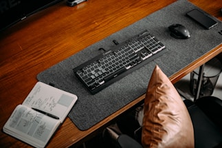 A clean workspace with a laptop and a notebook on a wooden desk.