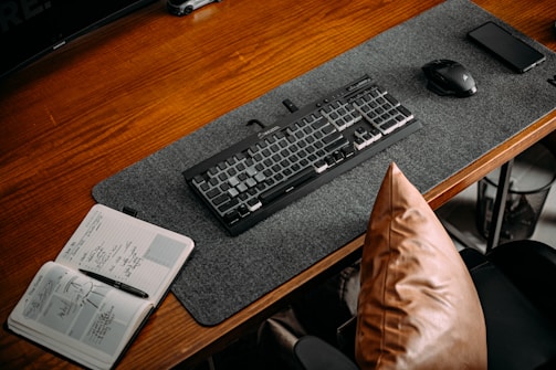 A clean workspace with a laptop and a notebook on a wooden desk.