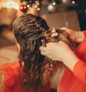 Hands skillfully braiding hair with a background of the cozy djekan shop interior