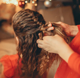 Hands skillfully braiding hair with a background of the cozy djekan shop interior