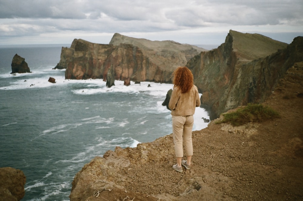 a woman standing on a cliff overlooking the ocean