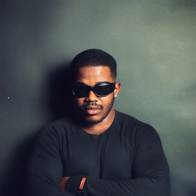 Model in a sleek black oversized t-shirt against a deep black background with soft gold glow accents.