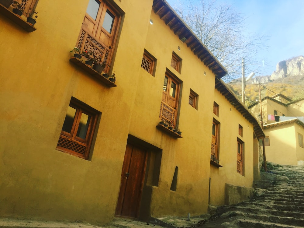 a yellow building with wooden windows and stairs