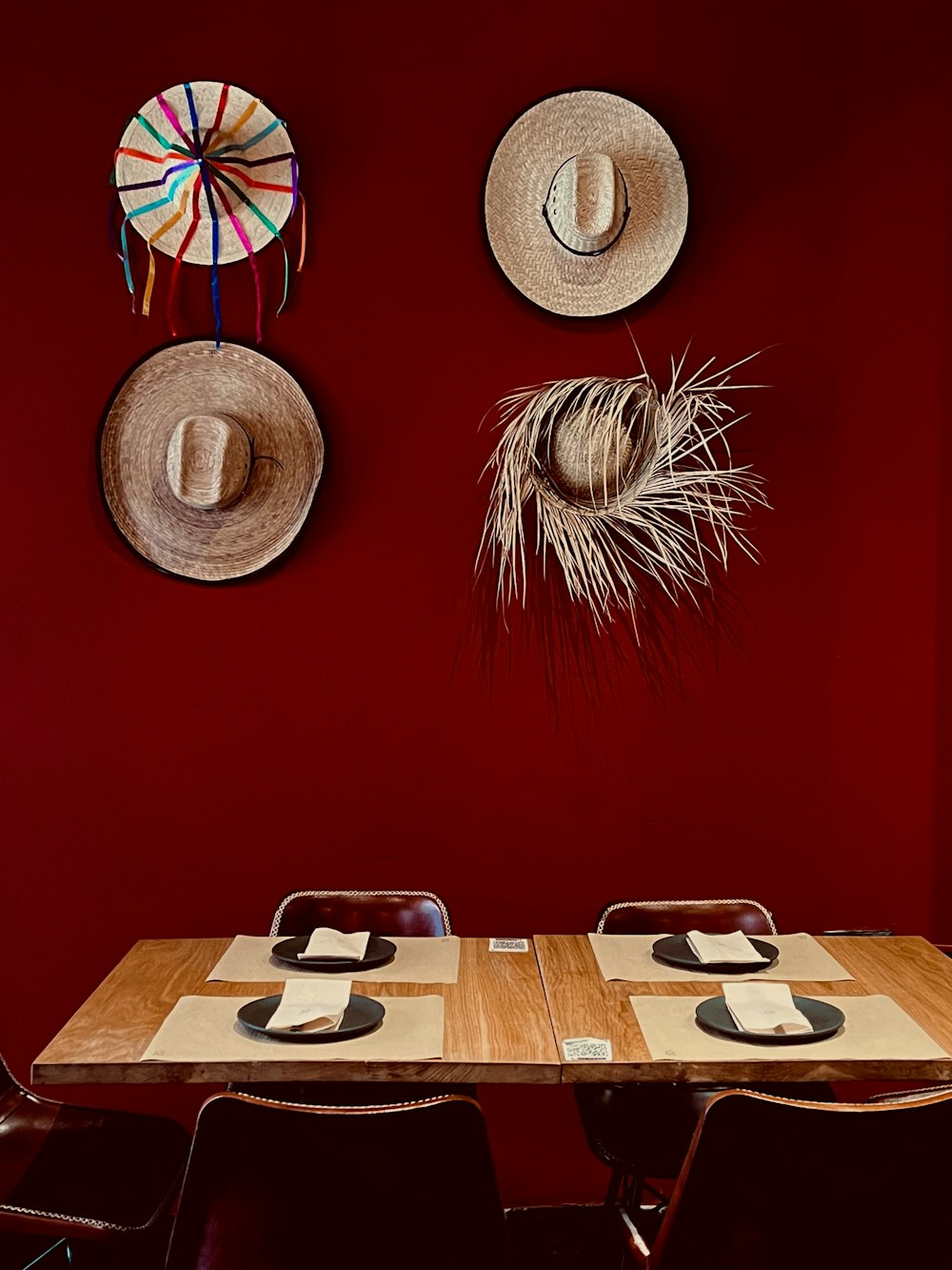 dois chapéus pendurados em uma parede vermelha acima de uma mesa de madeira