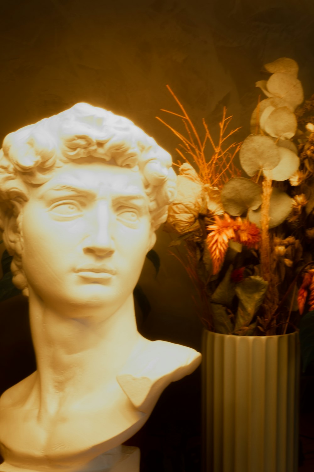 a bust of a man next to a vase of flowers