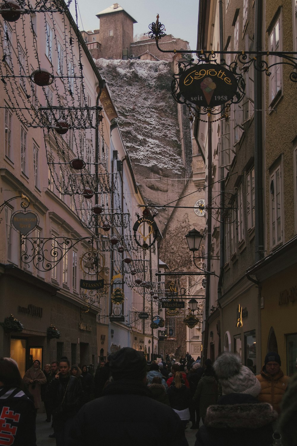 a group of people walking down a street next to tall buildings