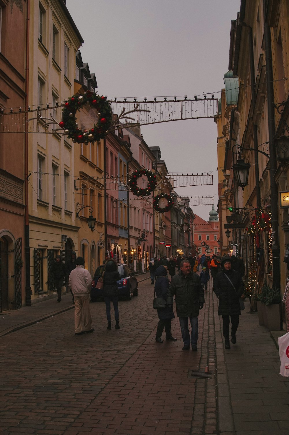 a group of people walking down a street next to tall buildings