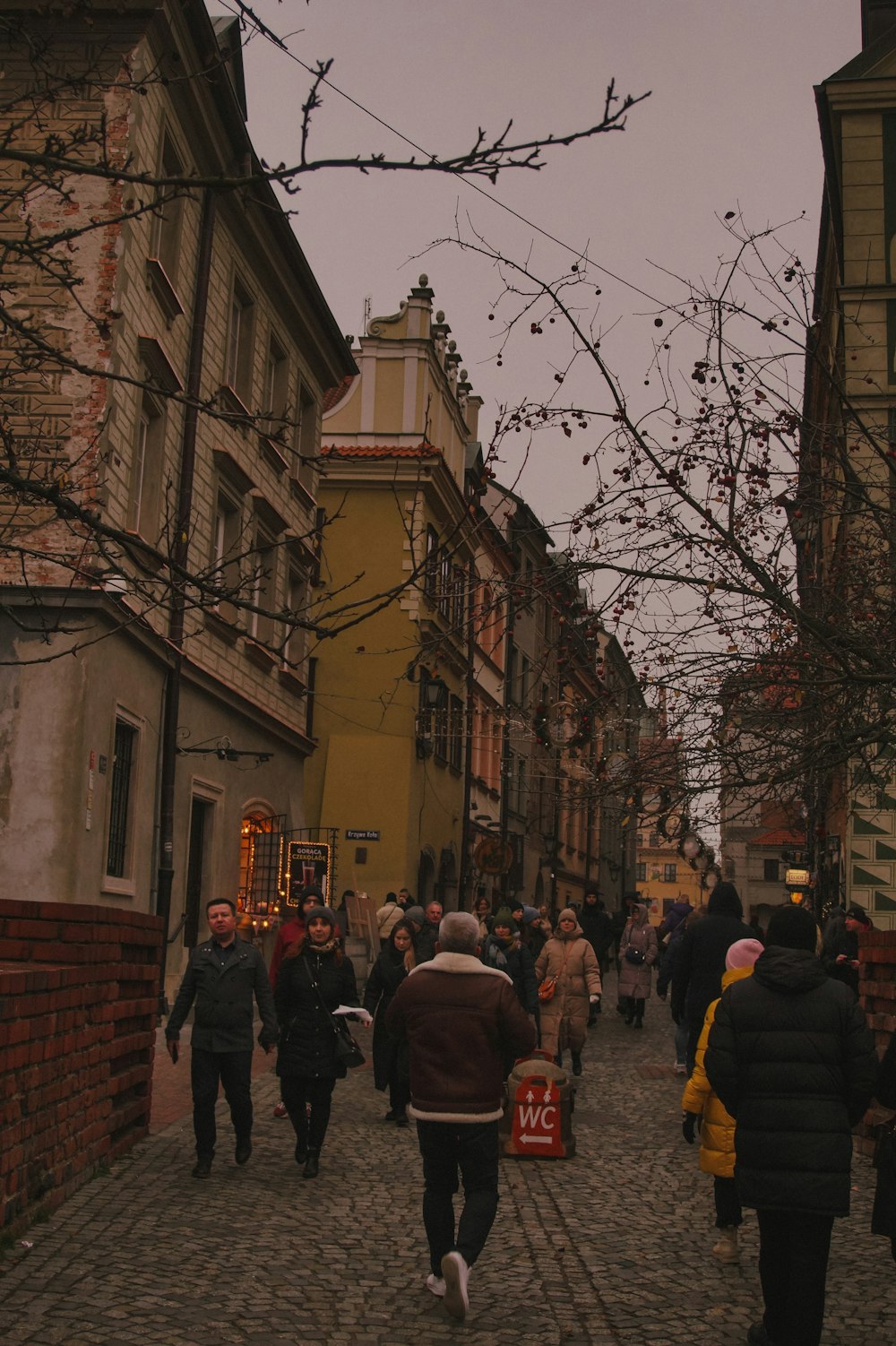 a group of people walking down a street next to tall buildings