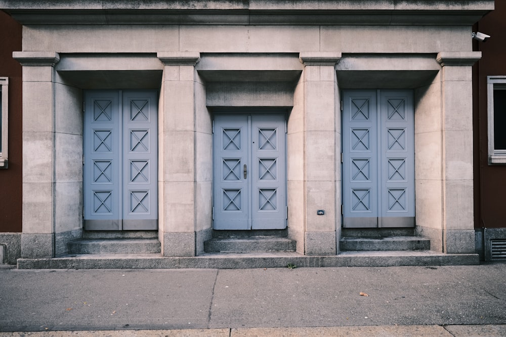 a couple of blue doors sitting on the side of a building