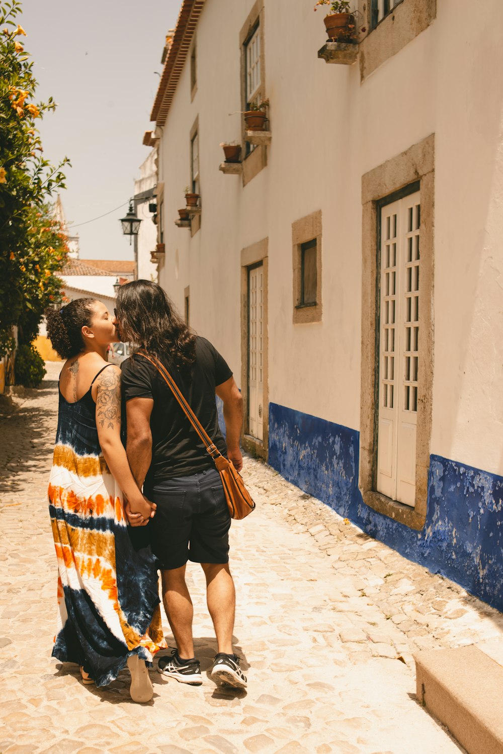 a man and a woman kissing on a cobblestone street