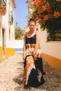 a woman in a colorful dress standing on a cobblestone street