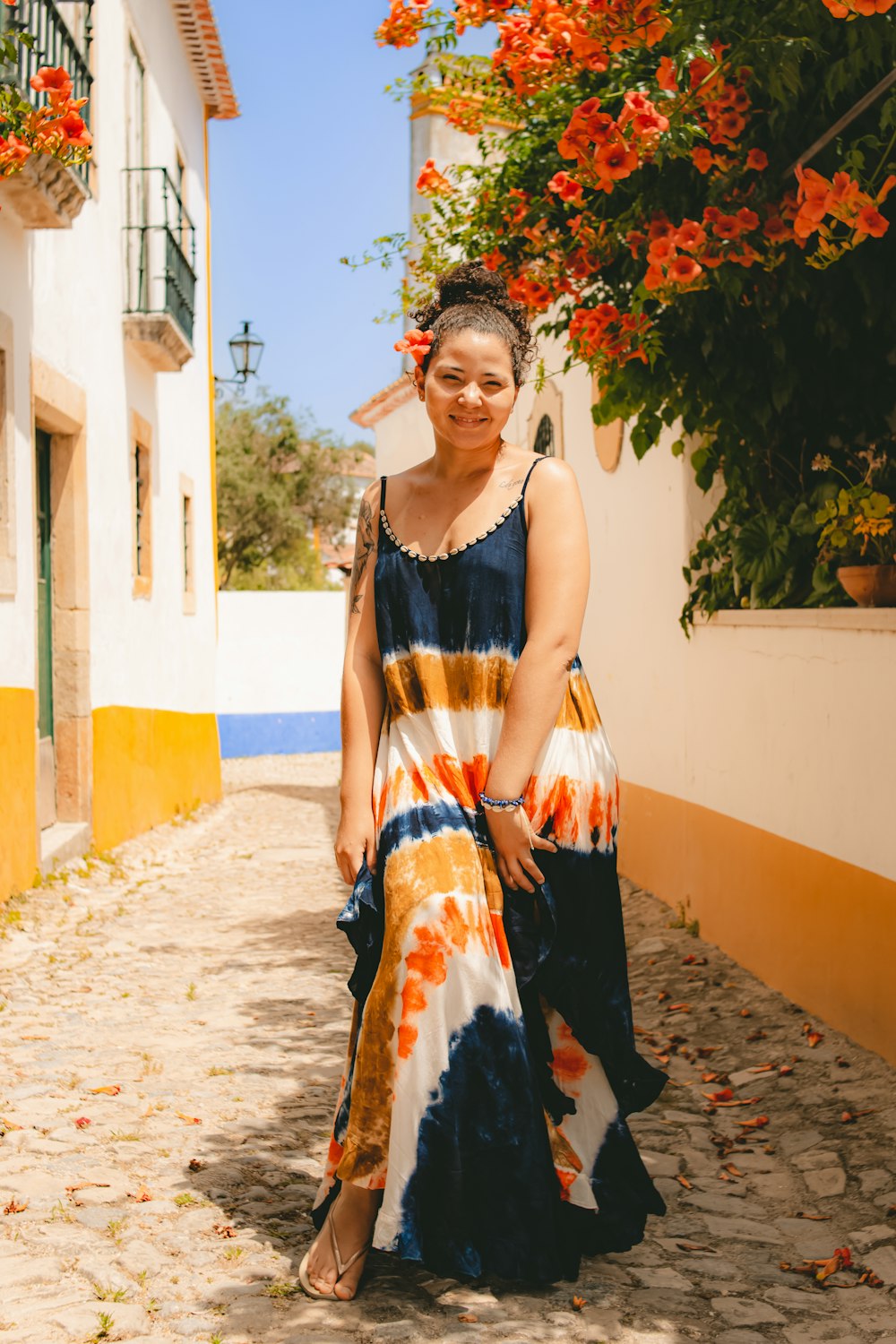 a woman in a colorful dress standing on a cobblestone street