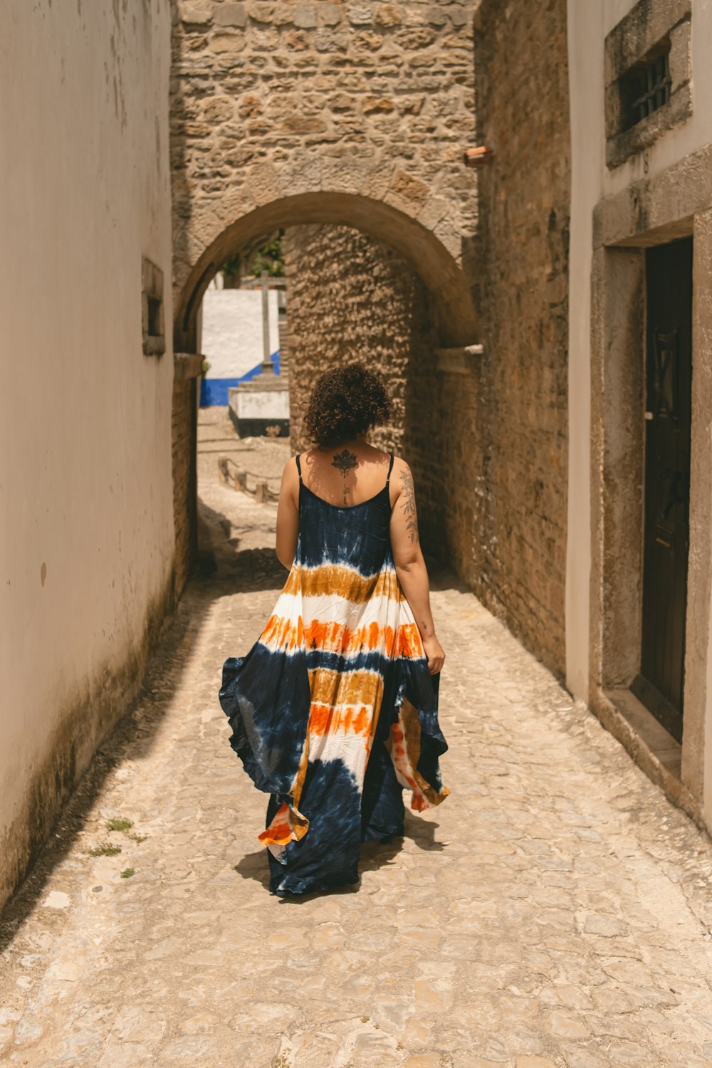 a woman walking down a narrow alley way