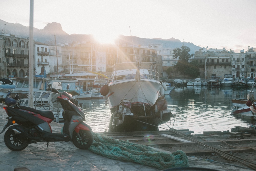 uma scooter a motor estacionada ao lado de um barco em um porto