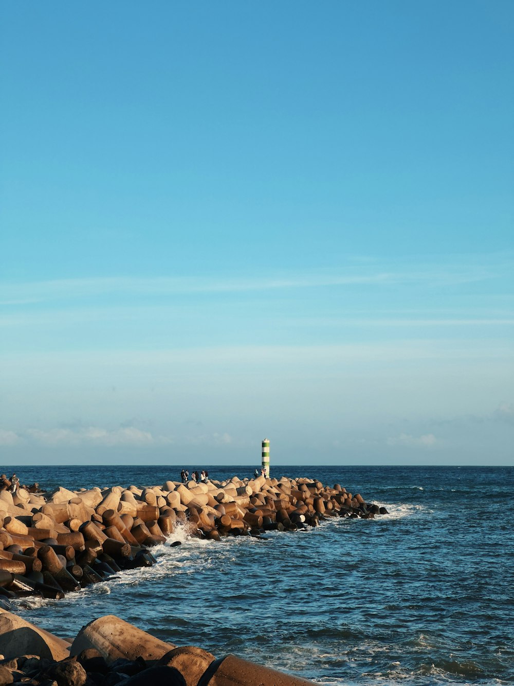 a person standing on a rock wall next to the ocean