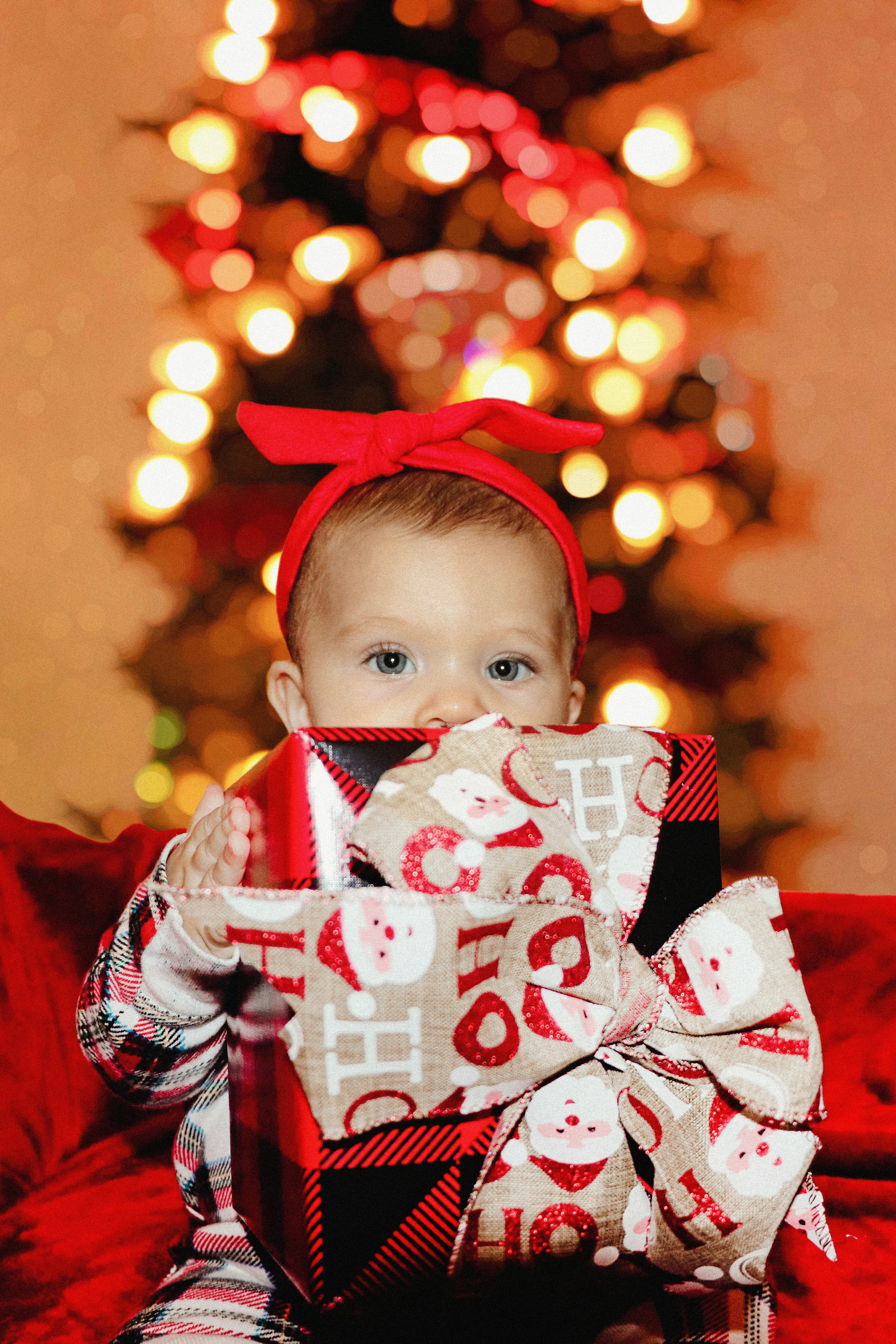 a baby sitting on a couch holding a wrapped present