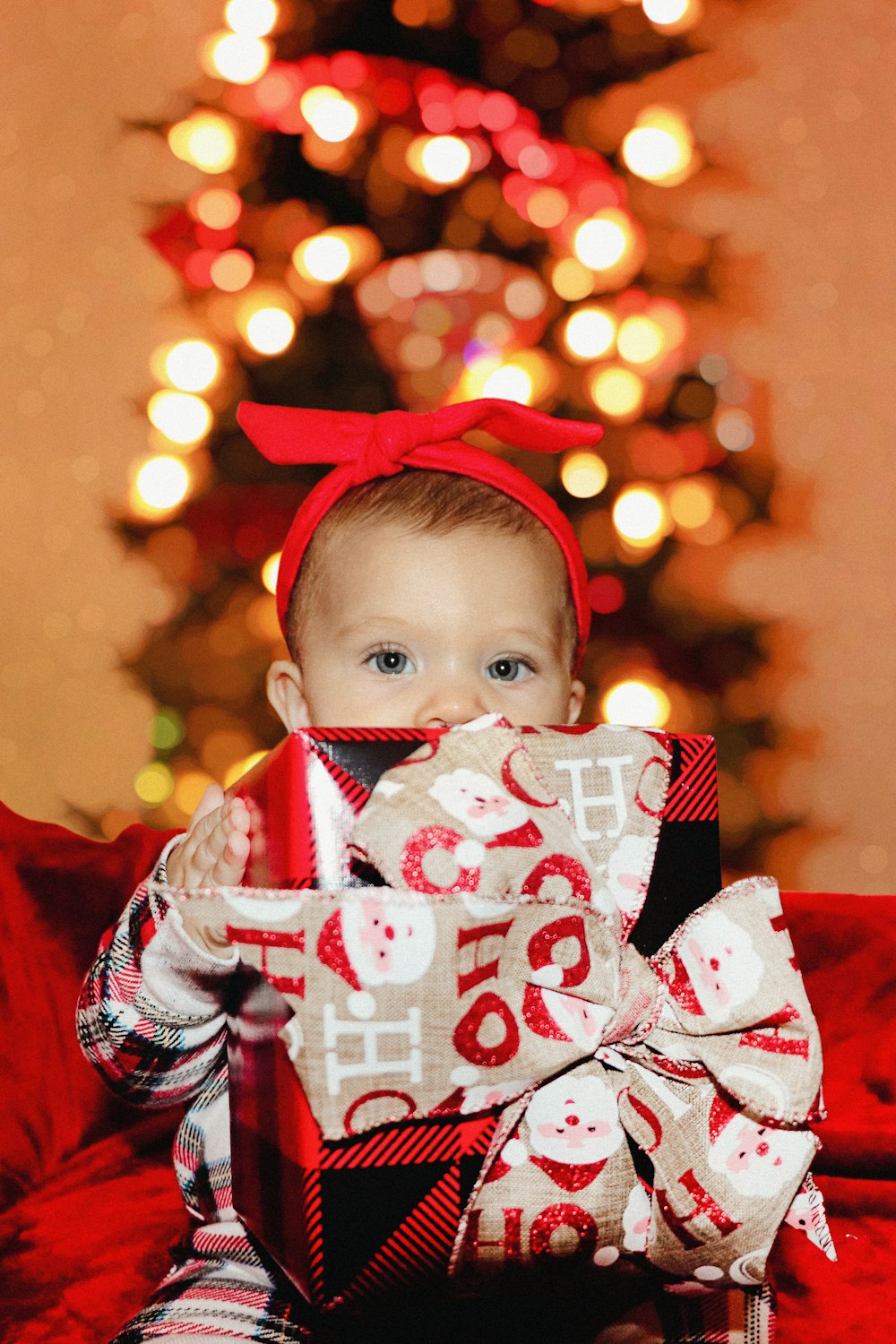 a baby sitting on a couch holding a wrapped present