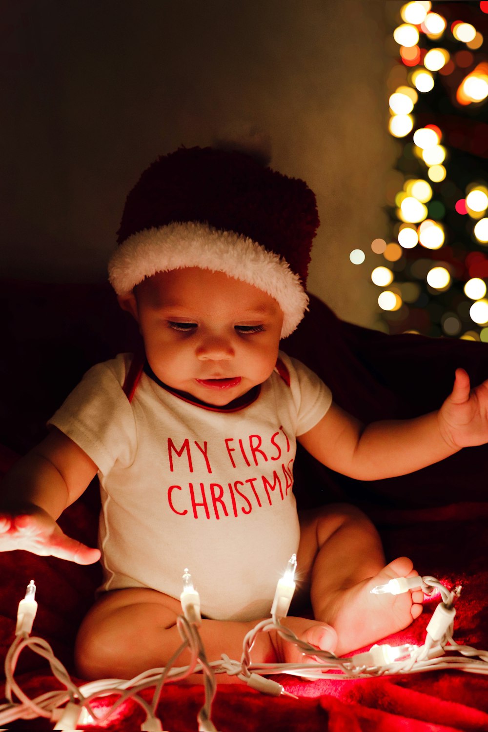 a baby sitting on a bed with a christmas hat on