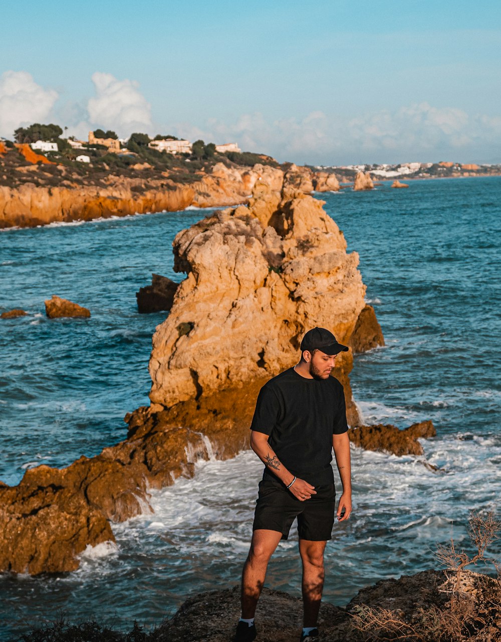 a man standing on a rock next to the ocean