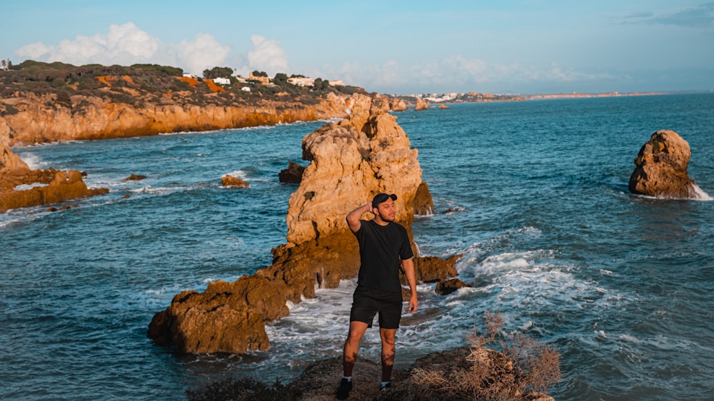 a man standing on a rock next to the ocean
