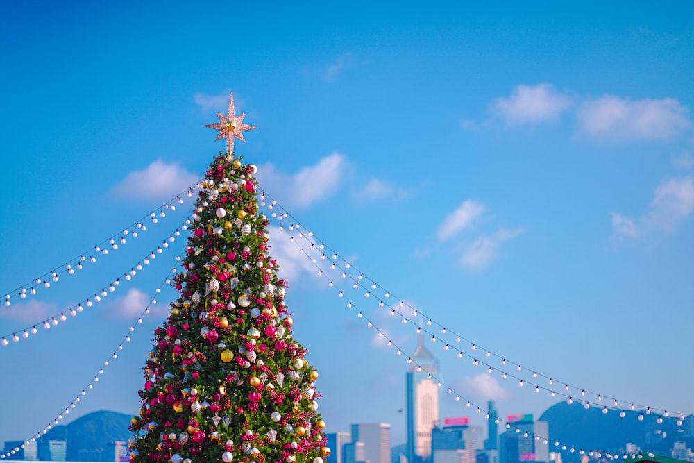 a large christmas tree in front of a city skyline