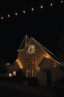 a lighted house with a clock on the front of it