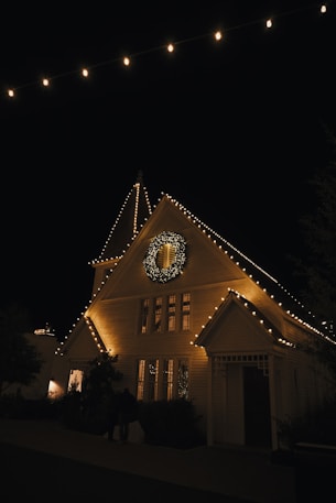 a lighted house with a clock on the front of it