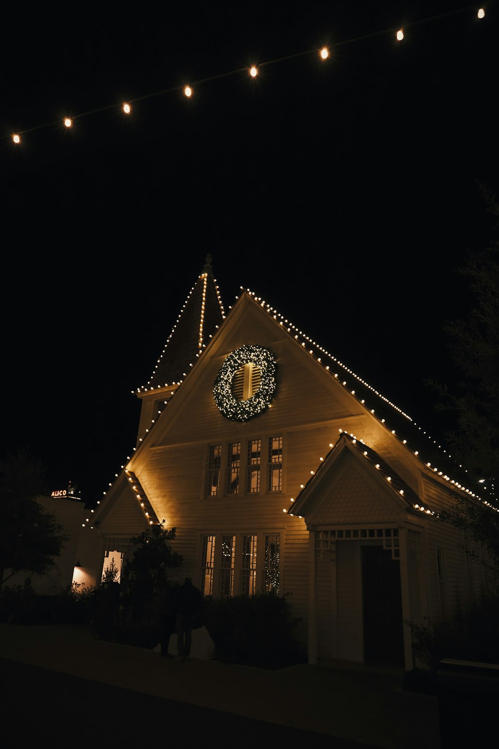 a lighted house with a clock on the front of it