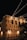 String lights are hung across a night sky, illuminating a building facade with the large, bold text 'EVERYONE HAS A STORY WORTH TELLING'. The building is adorned with industrial-style architecture including staircases and lamps.