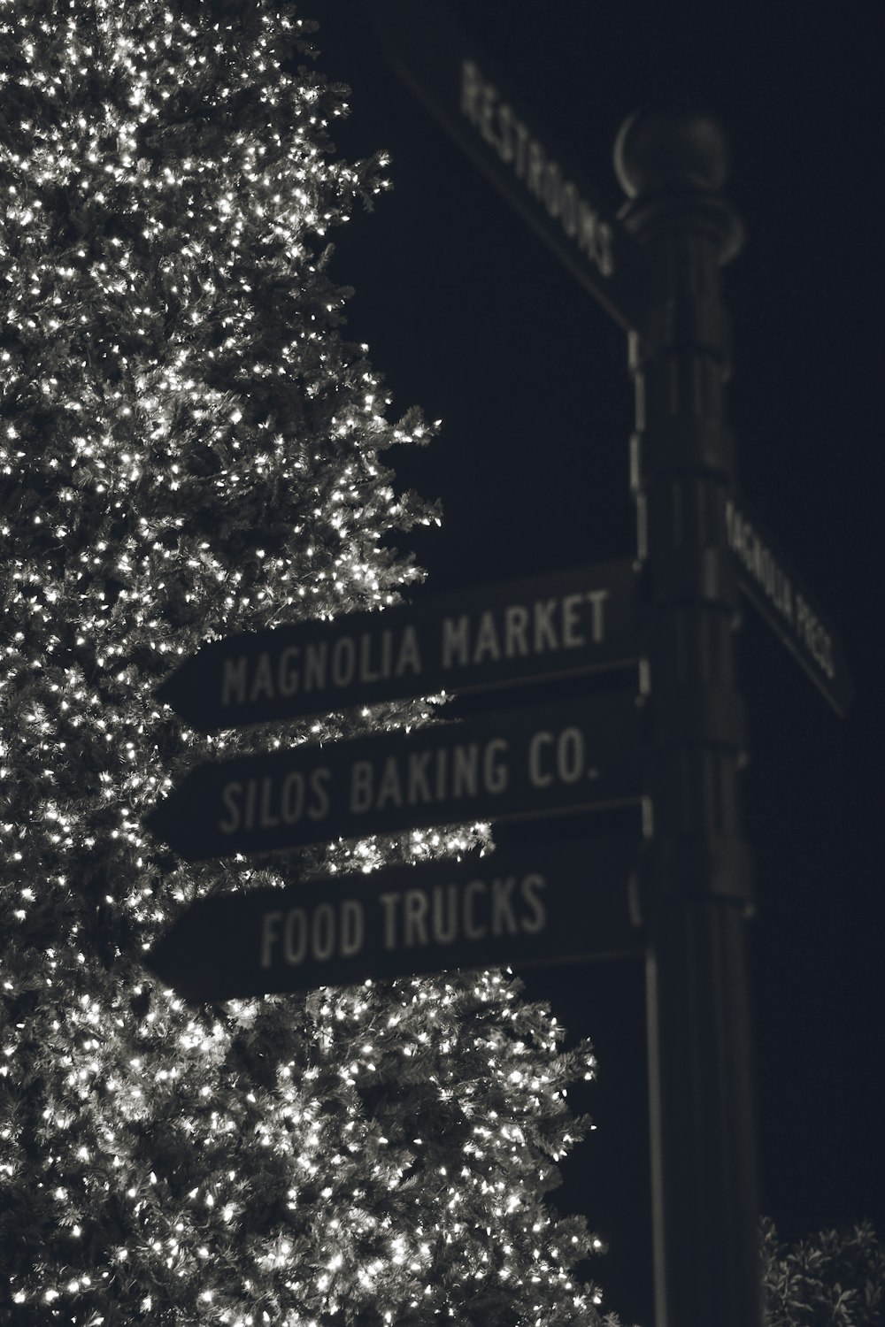 a christmas tree is lit up in front of a street sign