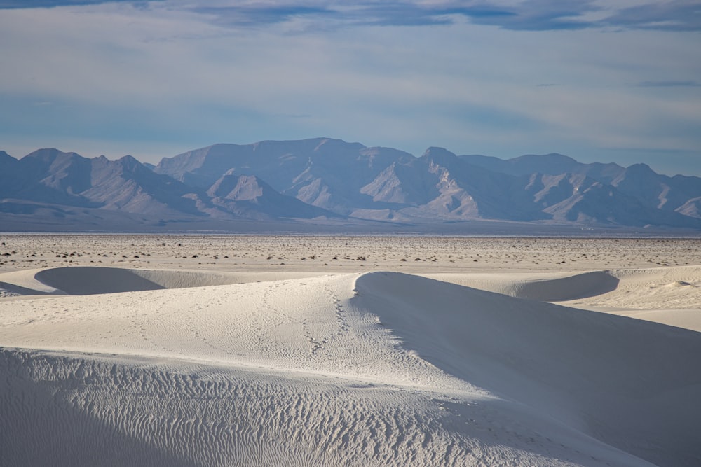 a vast expanse of white sand with mountains in the background