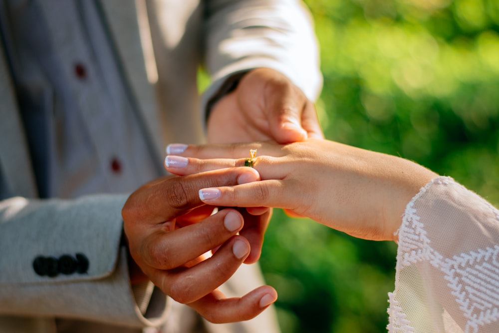 a man and a woman holding hands with a wedding ring