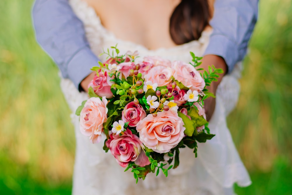 a bride holding a bouquet of pink roses
