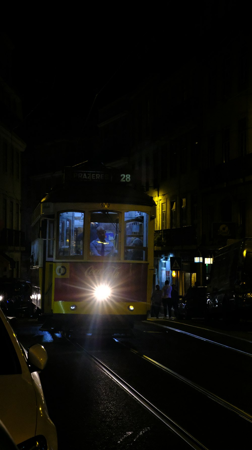 a yellow and red bus driving down a street at night