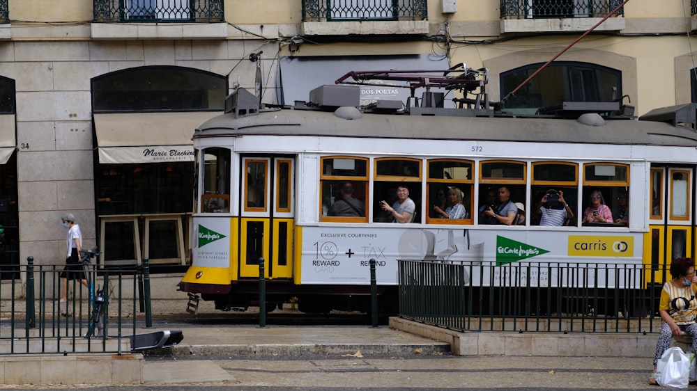 a yellow and white trolley car traveling down a street