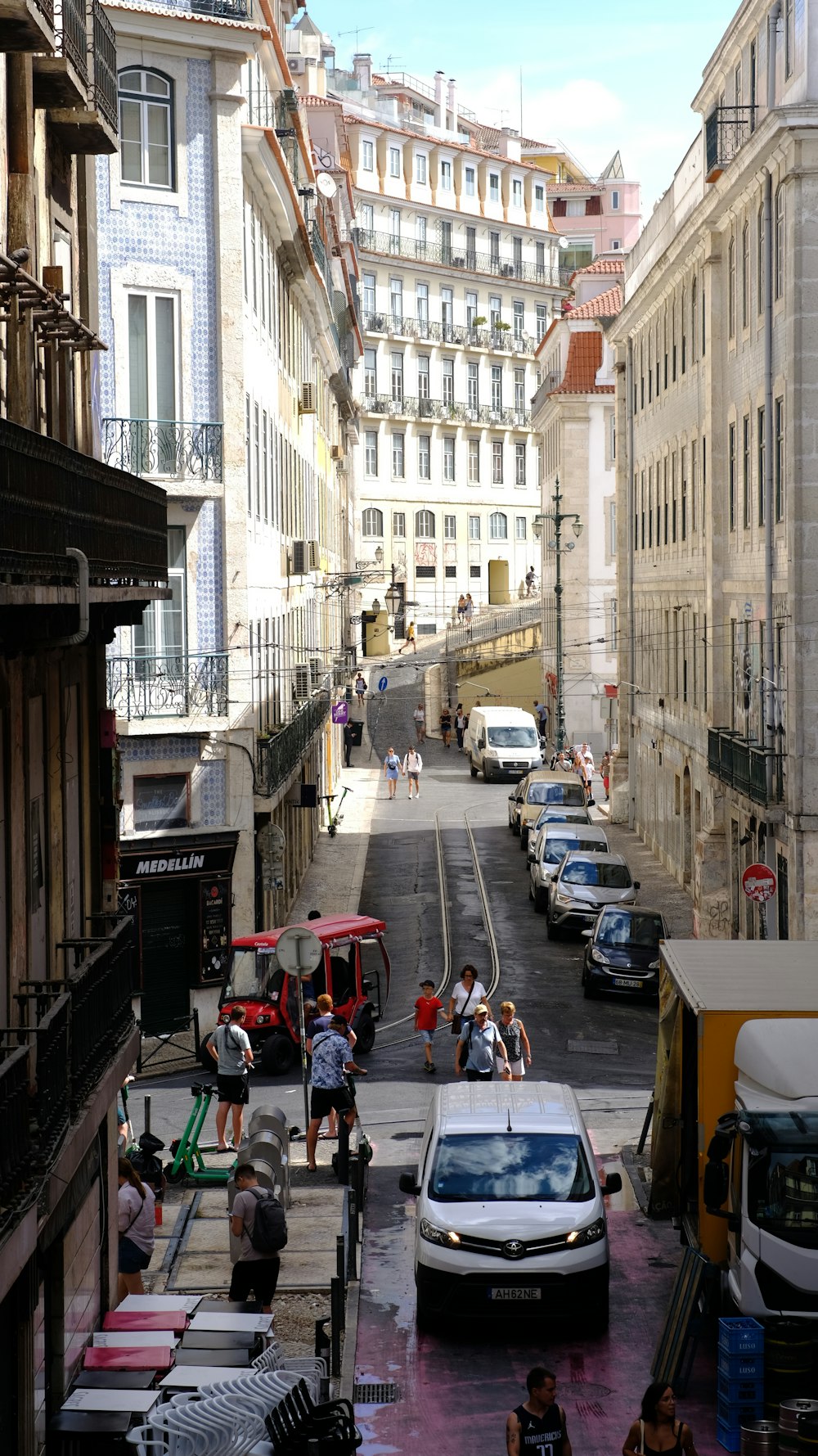 a group of people walking down a street next to tall buildings