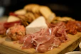 a wooden cutting board topped with meat and cheese