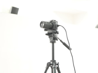 Close-up of a professional camera on a tripod against a minimalist black and white backdrop