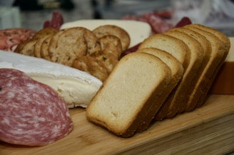 Close-up of fresh sliced meats and cheeses arranged on a wooden board.
