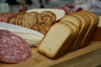 Close-up of fresh sliced meats and cheeses arranged on a wooden board.