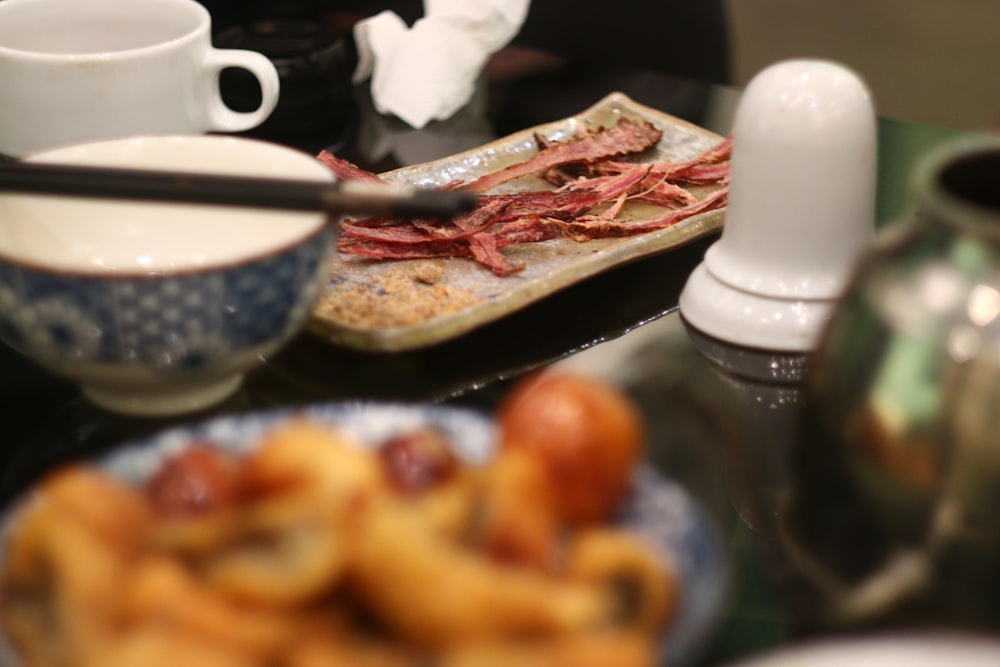 a table topped with plates of food and cups